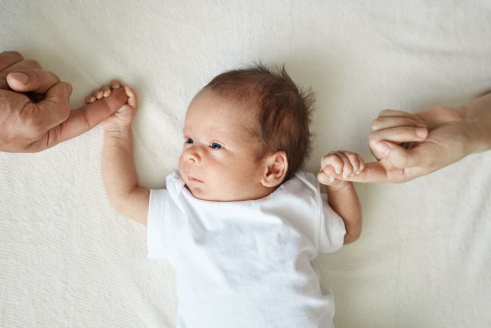 Infant holding onto adult fingers